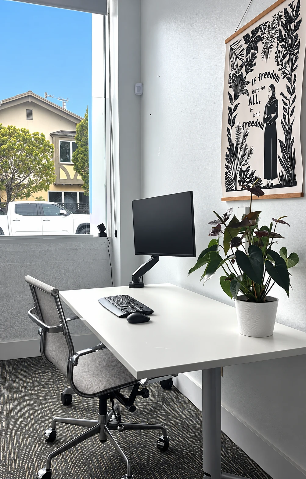 A quiet desk with a monitor beside a bright window